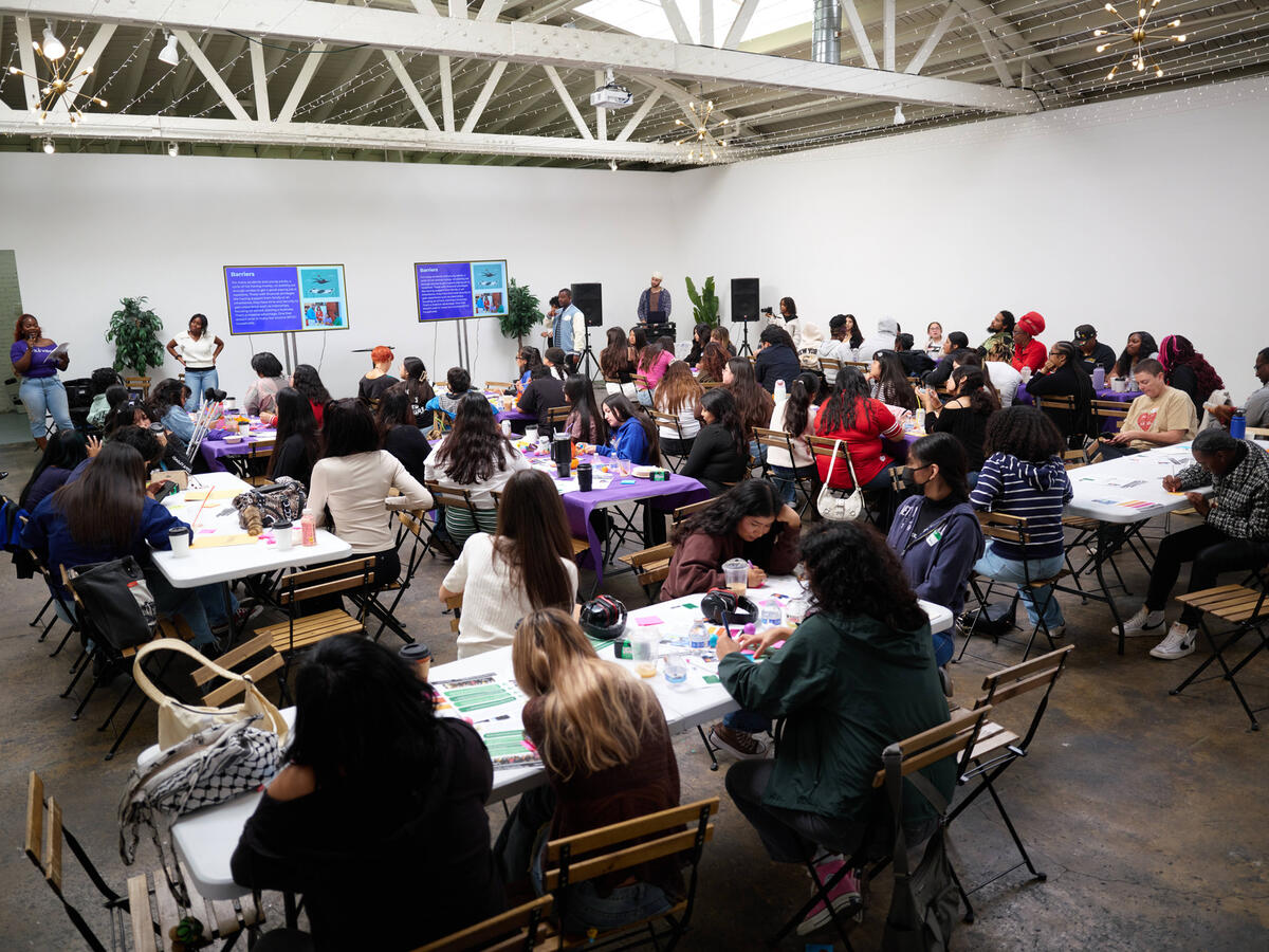 A wide view of attendees seated at tables throughout the October Youth Summit venue.