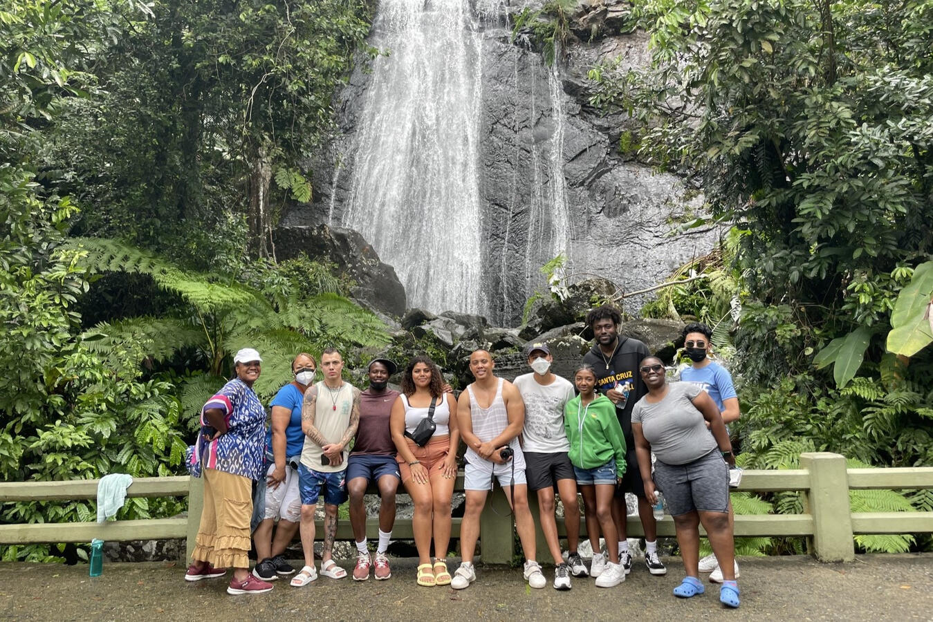 The fellowship cohort poses together in front of a waterfall in a Puerto Rico rainforest.