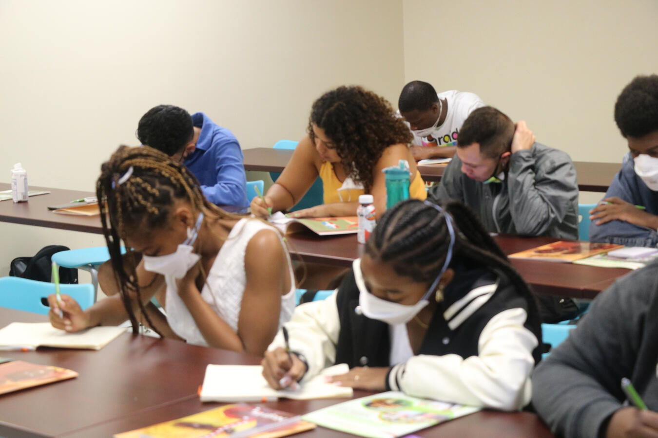 Delegation members sit together writing and working during an indoor workshop session.
