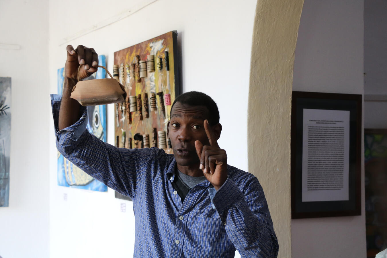 A man raises his fist in front of framed artwork inside a gallery in Havana.