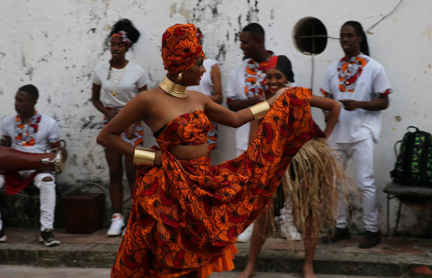 A dancer in a red and gold dress performs alongside musicians in white during a ceremony in Havana.