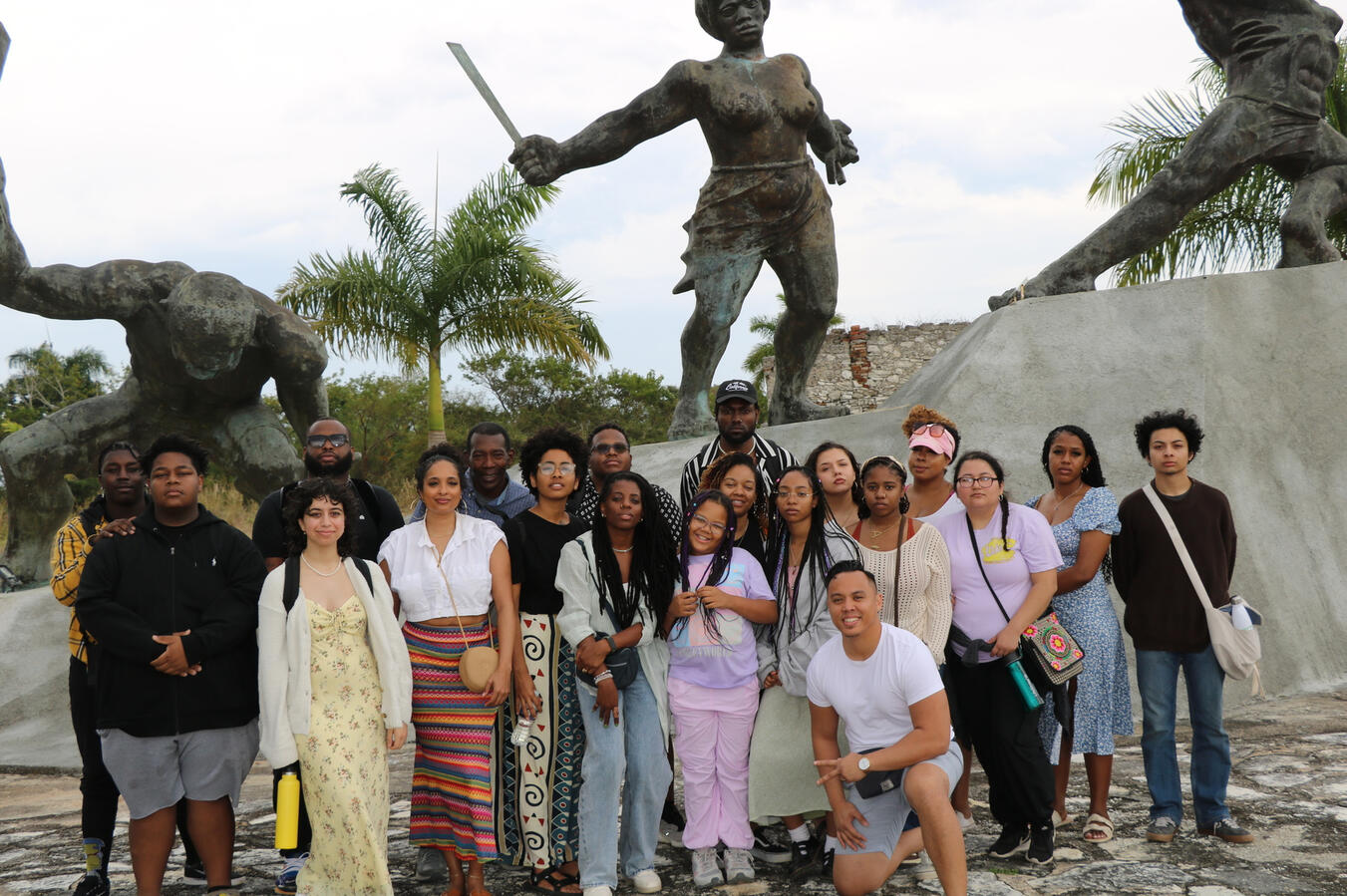 The fellowship cohort poses together in front of a large bronze statue in Cuba.