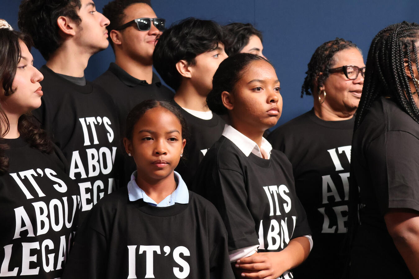 A large group of young advocates pose energetically on steps outside a government building.