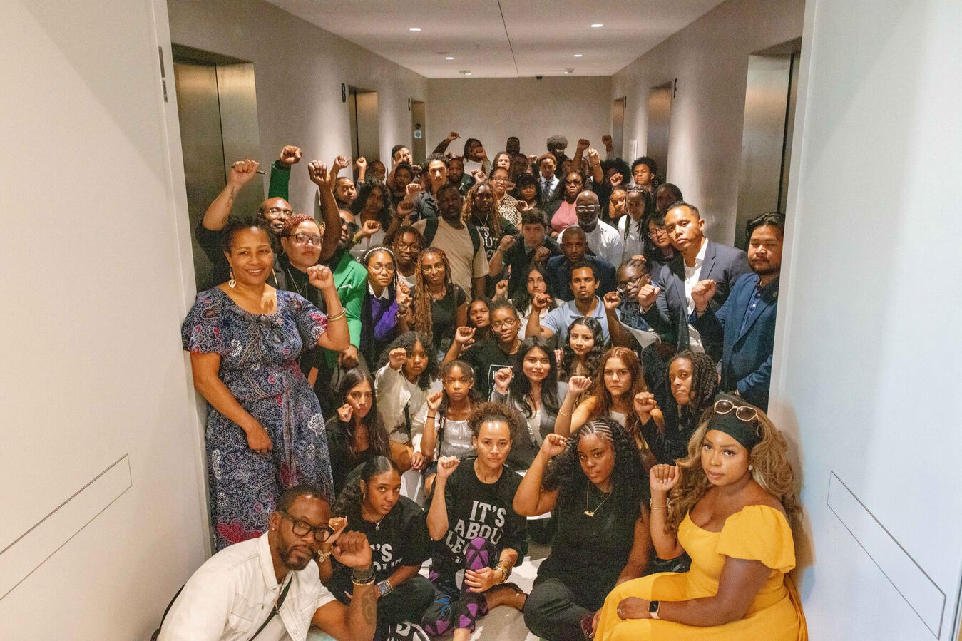 A large group of student and community advocates pose together inside a Capitol hallway.