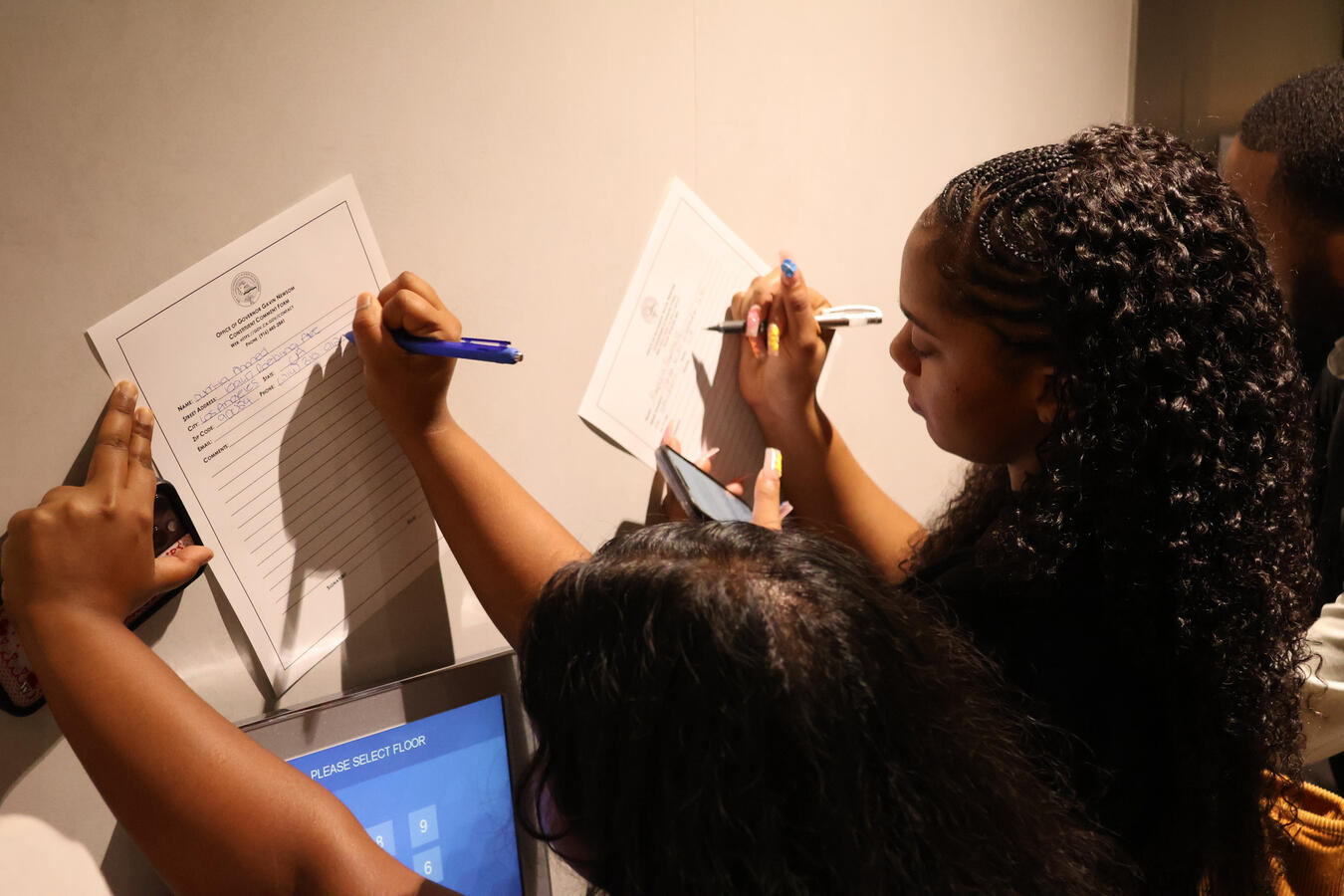 Two people write on a poster board with markers ahead of the Capitol advocacy day.