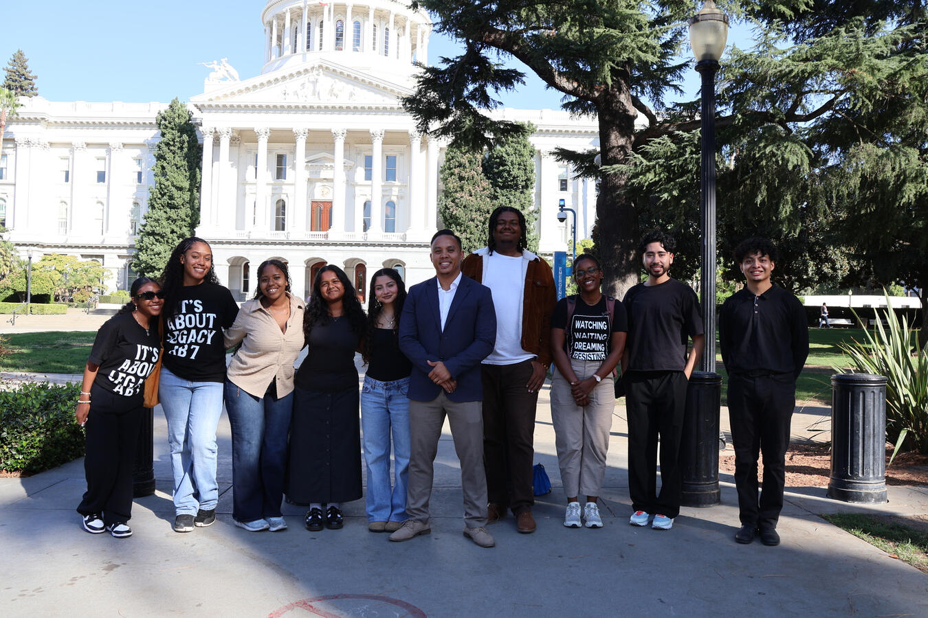A group of advocates stands together on the lawn outside the California State Capitol.