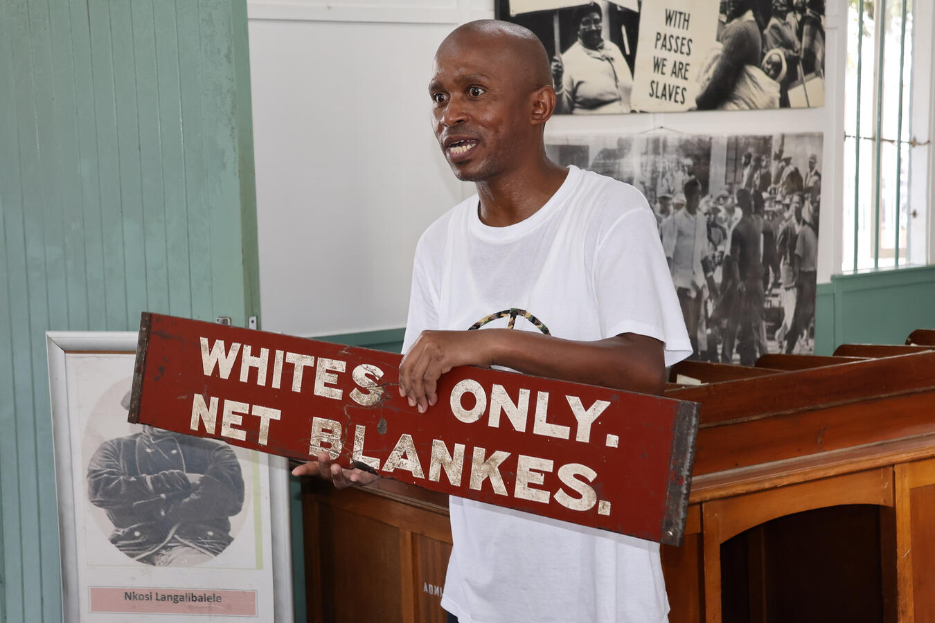 A speaker holds up a Whites Only, Net Blankes sign from South Africa's apartheid era.