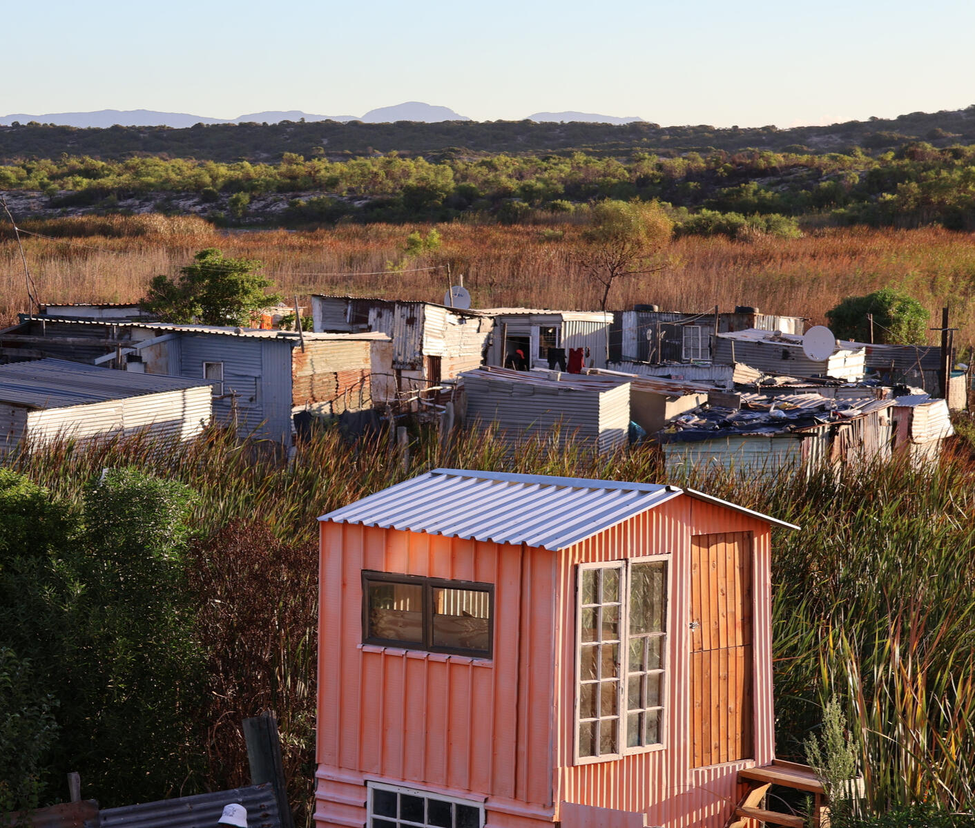 Housing in a Cape Town Township Small homes, including a brightly painted shed, sit along a dirt road in a Cape Town township.